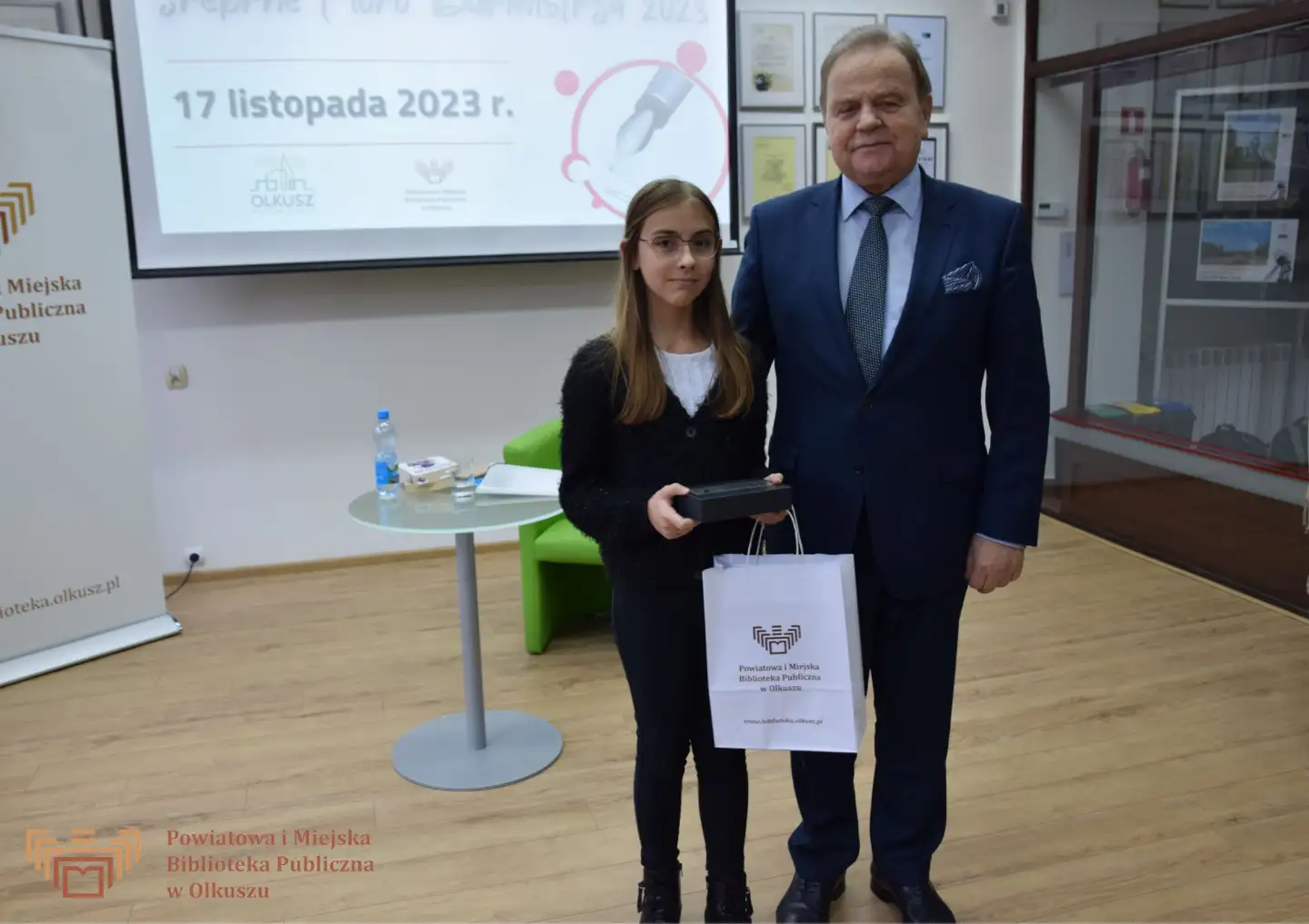 Zdjęcie przedstawia Burmistrza Miasta i Gminy Olkusz, który wręcza nagrodę dziewczynce - laureatce konkursu "Z polszczyzną za Pan brat".